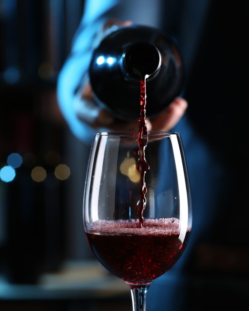 Bartender,Pouring,Red,Wine,From,Bottle,Into,Glass,Indoors,,Closeup